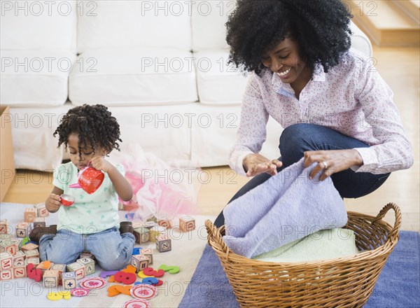 Mother folding laundry while daughter plays