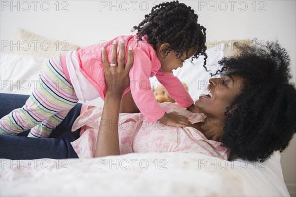 Mother and daughter playing on bed