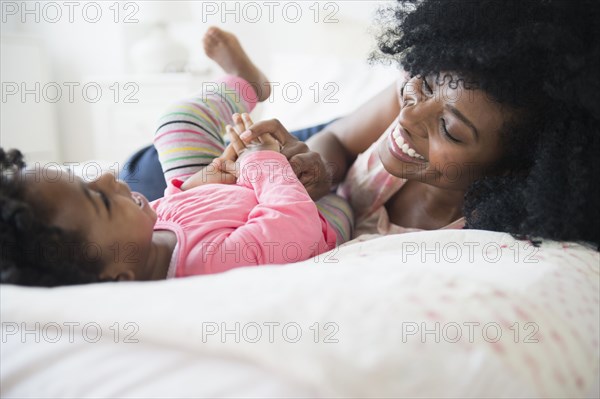 Mother and daughter playing on bed