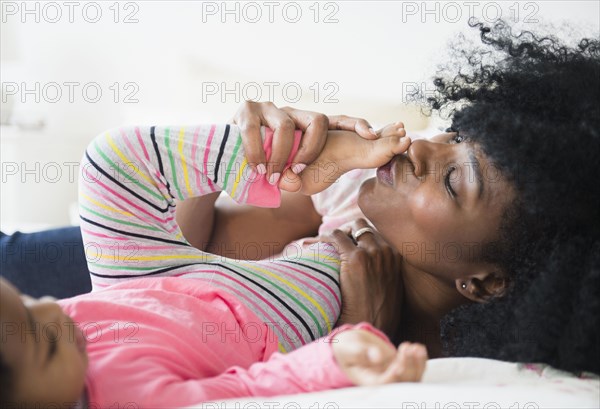 Mother and daughter playing on bed