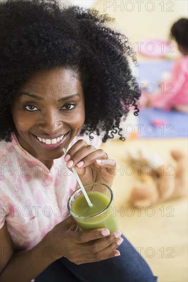 Smiling woman drinking green juice