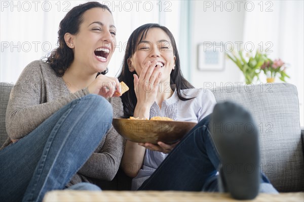 Women laughing on sofa together