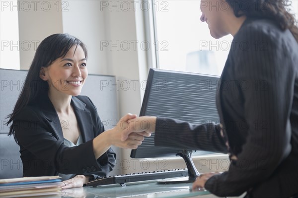 Businesswomen shaking hands in office