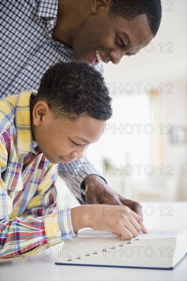 Father helping son reading dictionary