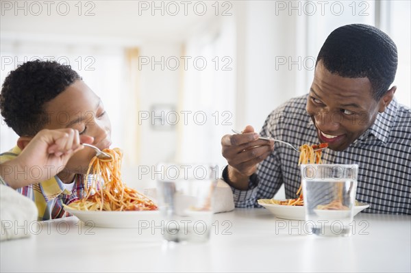 Father and son eating together at table