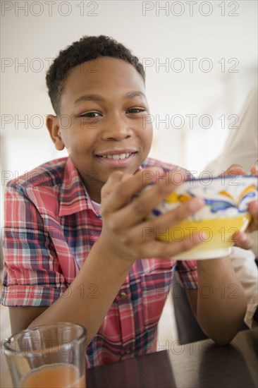 Black boy eating breakfast in kitchen