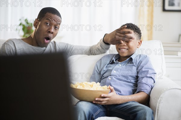 Father and son watching television on sofa