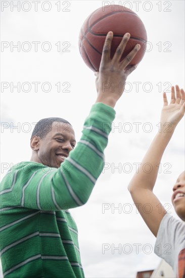 Father and son playing basketball outdoors