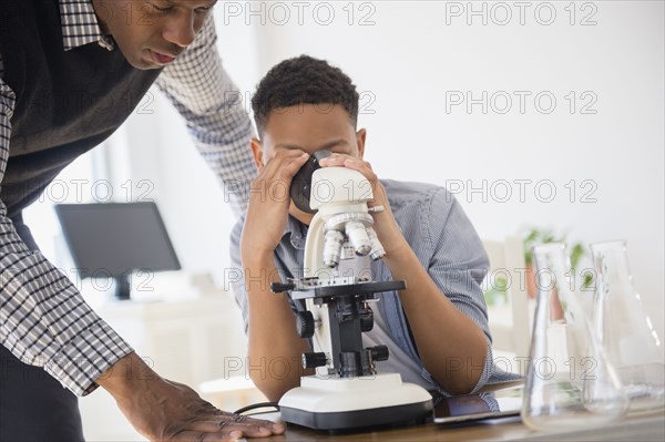 Teacher helping student use microscope in science class