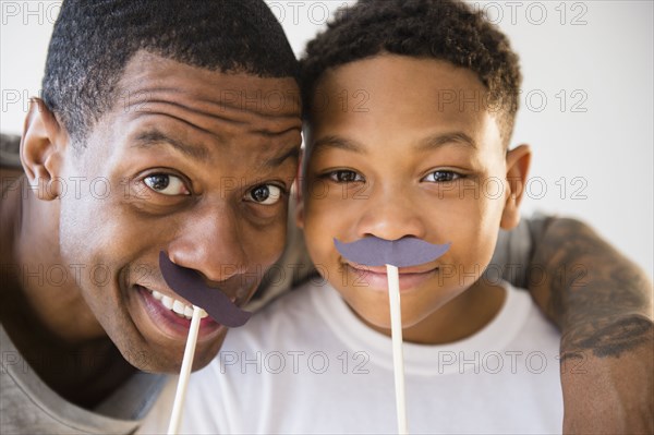 Father and son playing with fake mustaches