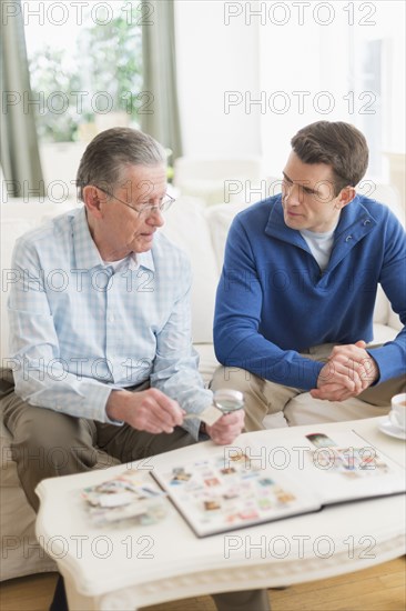 Caucasian father and son examining stamp collection