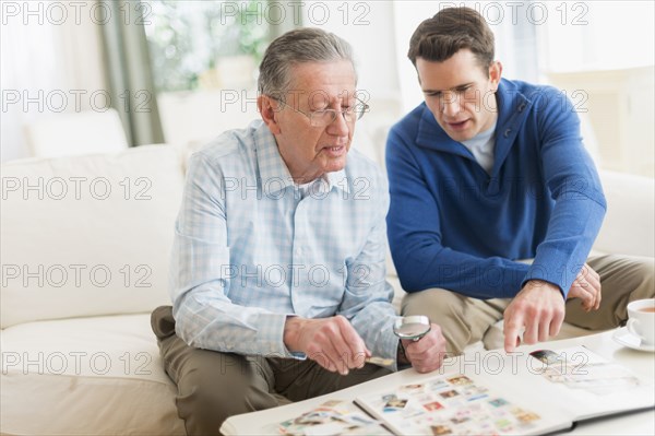 Caucasian father and son examining stamp collection