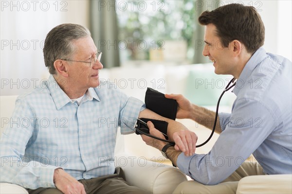 Caucasian doctor taking patient's blood pressure at home