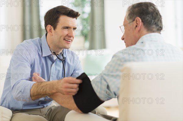 Caucasian doctor taking patient's blood pressure at home