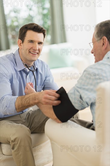 Caucasian doctor taking patient's blood pressure at home