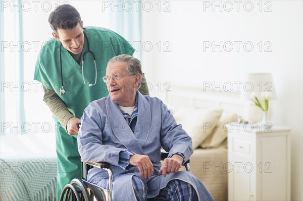 Caucasian nurse wheeling patient in home