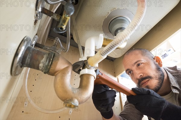 Hispanic plumber working under sink