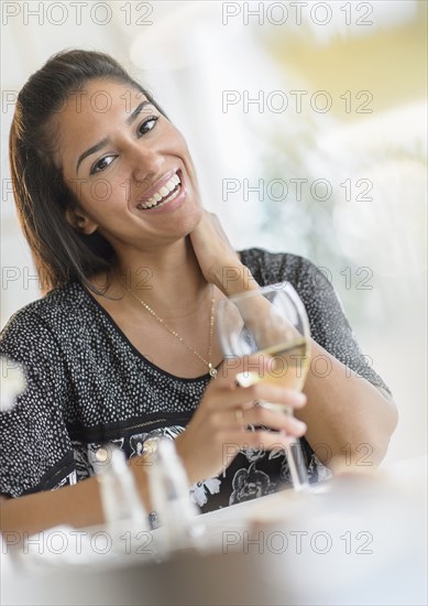 Hispanic woman drinking wine at dinner