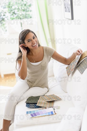 Hispanic woman with fabric swatches on sofa