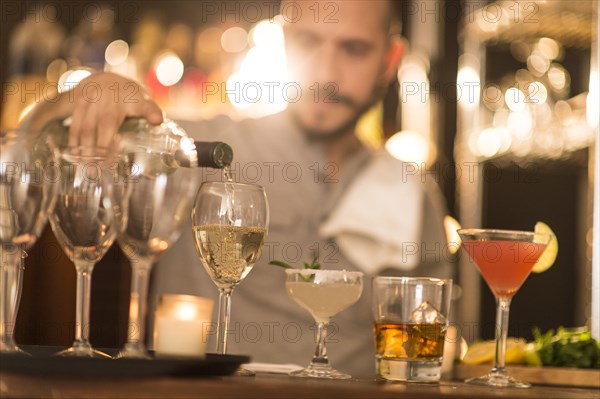 Hispanic bartender pouring drinks at bar