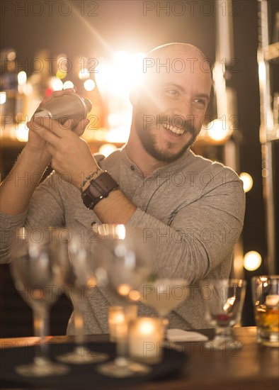 Hispanic bartender making drinks at bar