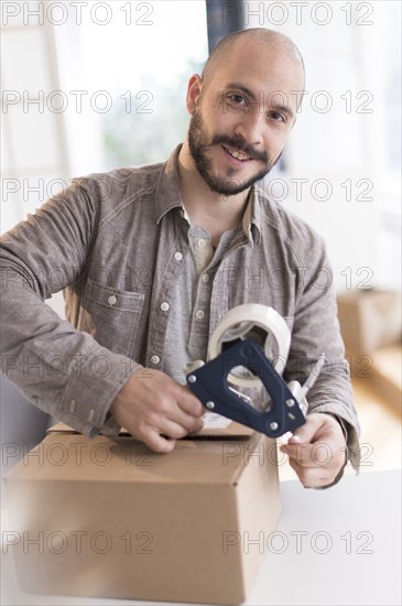 Hispanic man taping cardboard box