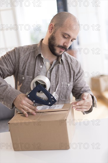 Hispanic man taping cardboard box