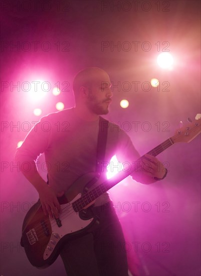 Hispanic musician playing electric guitar on stage