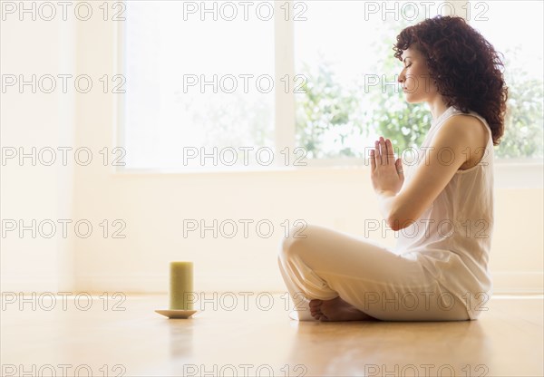 Hispanic woman meditating with candle