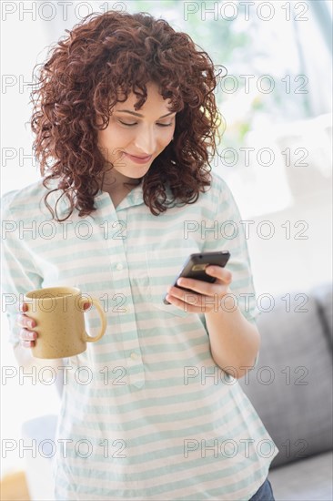 Hispanic woman using cell phone in living room