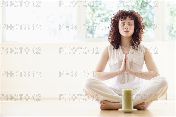 Hispanic woman meditating with candle