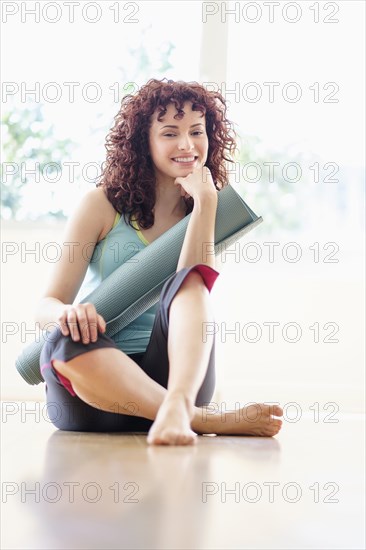 Hispanic woman holding yoga mat on floor