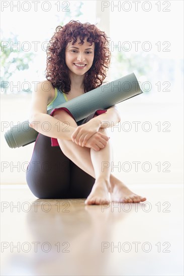 Hispanic woman holding yoga mat on floor