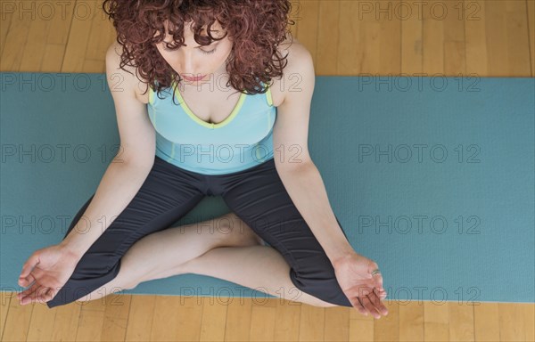 Hispanic woman meditating on yoga mat