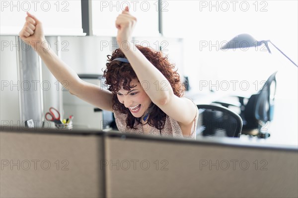 Hispanic businesswoman cheering in office