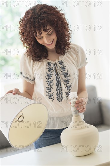 Hispanic woman changing light bulb