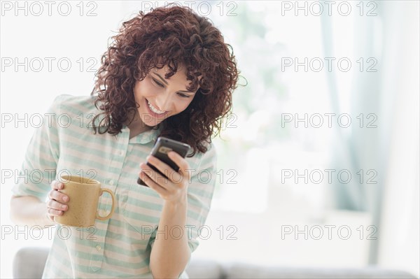 Hispanic woman using cell phone in living room