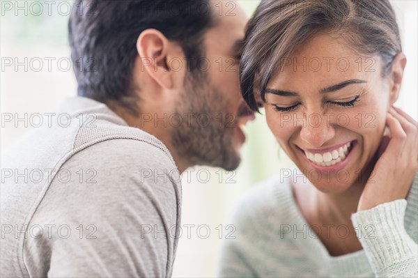 Couple whispering together indoors