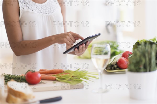 Hispanic woman cooking with digital tablet in kitchen