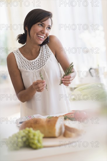 Hispanic woman talking on cell phone and cooking in kitchen