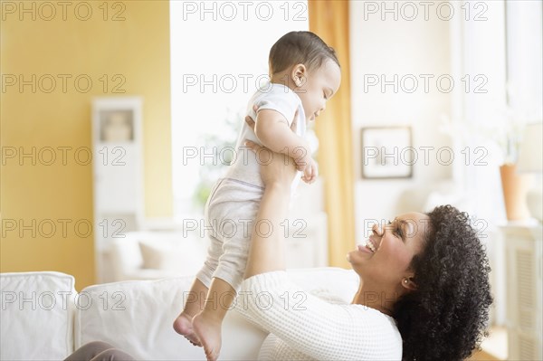 Mixed race mother playing with baby on sofa