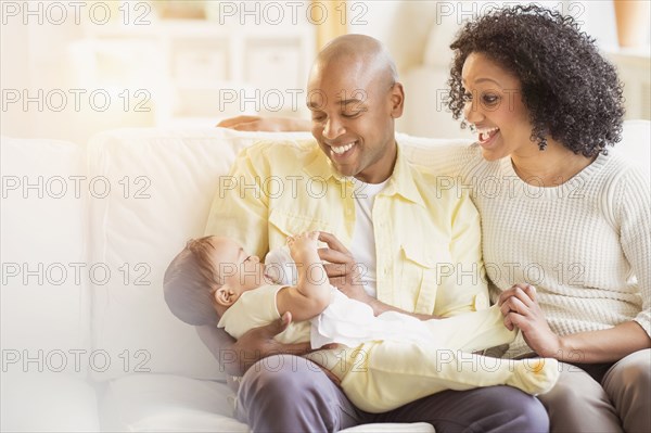 Parents feeding baby on sofa