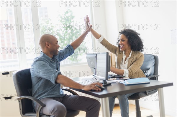 Business people high fiving in office