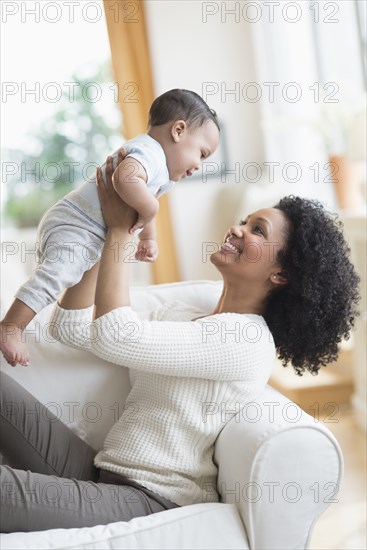 Mixed race mother playing with baby on sofa