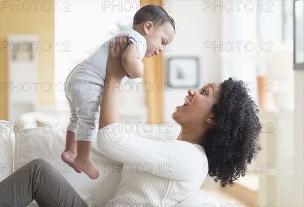 Mixed race mother playing with baby on sofa