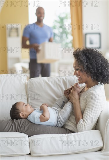 Mixed race mother playing with baby on sofa