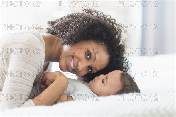 Mixed race mother playing with baby on bed