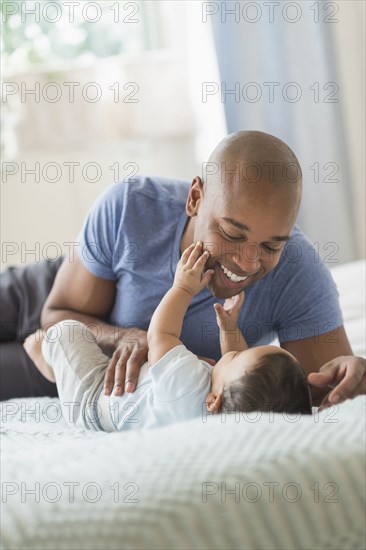 Father playing with baby on sofa