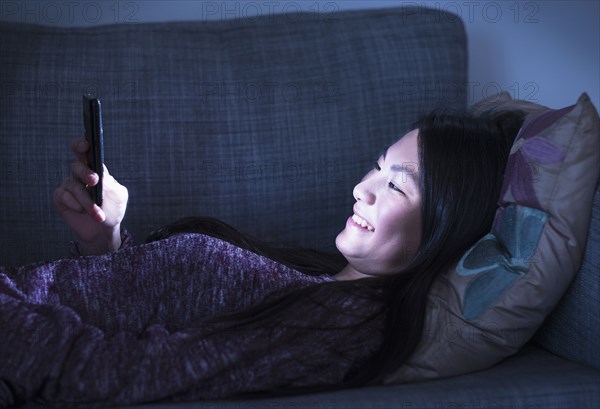 Mixed race teenage girl using cell phone on sofa