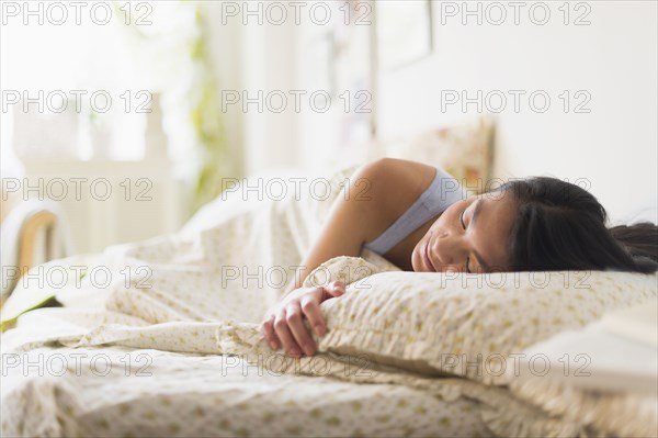 Mixed race teenage girl sleeping in bed